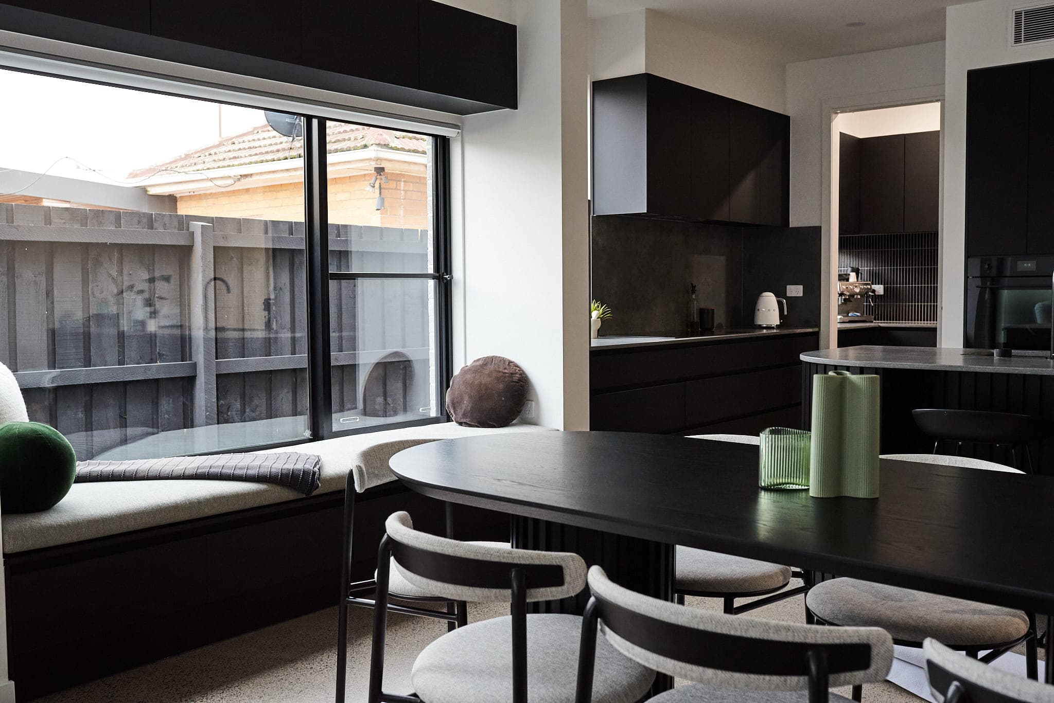 Black kitchen at Tassell with a dark oval dining table and upholstered window seat